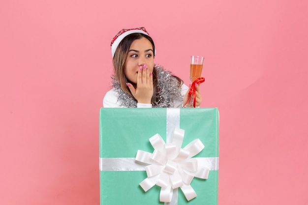 Foto grátis vista frontal de uma jovem comemorando o natal com uma bebida na parede rosa