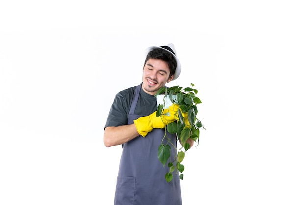 Foto grátis vista frontal jovem jardineiro masculino segurando a planta no fundo branco jardim árvore terra trabalho verde grama cor jardineiro flor