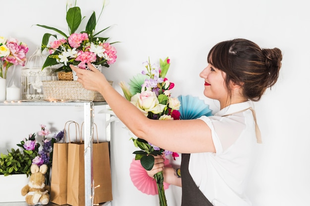 Foto grátis vista lateral da florista feminina olhando flores frescas na prateleira