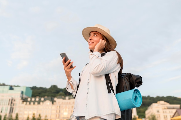 Foto grátis vista lateral de mulher com mochila e smartphone viajando