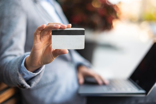 Foto grátis vista lateral de uma empresária segurando um cartão de crédito enquanto usa o laptop