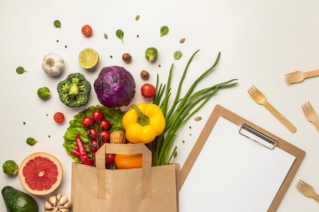 Foto grátis vista superior de uma variedade de vegetais em saco de papel com prancheta