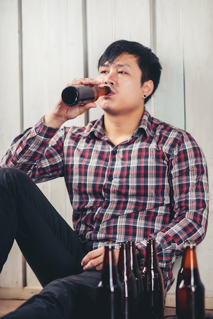 Kostenlose Foto alkoholischer asiatischer mann, der allein trinkendes bier sitzt