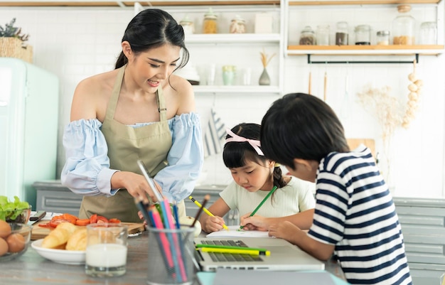 Kostenloses Foto asiatische alleinerziehende mutter, die essen zubereitet, während sie sich um ein kind in der küche zu hause kümmert, und eine alleinerziehende mutter