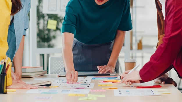 Kostenloses Foto asiatische geschäftsleute und geschäftsfrauen treffen sich mit brainstorming-ideen über kreative webdesign-planungsanwendungen und entwickeln ein vorlagenlayout für ein mobiltelefonprojekt, das in einem kleinen büro zusammenarbeitet.