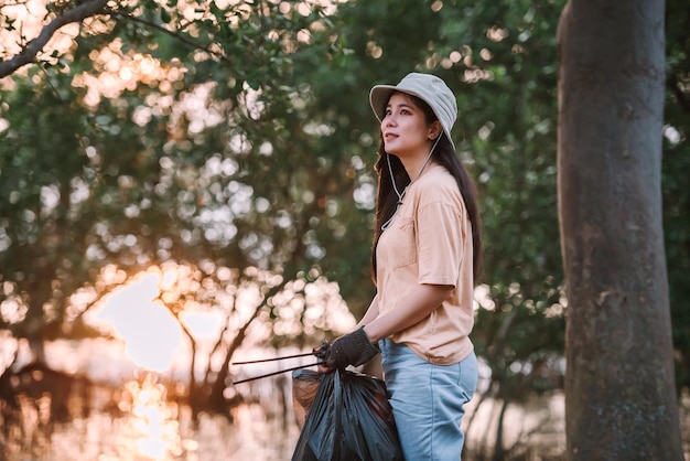 Kostenloses Foto asiatische umweltschutz-freiwillige sammeln plastik- und schaummüll in mülltüten auf öffentlichen parkflächen vvolunteering save world concept