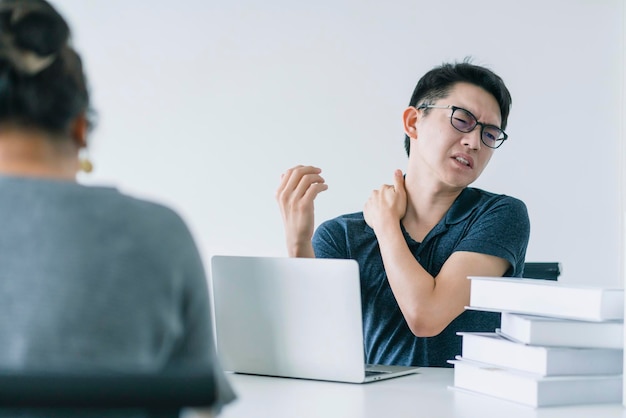 Kostenloses Foto asiatischer hart arbeitender mann mit bürosyndrom hat ein problem mit einem teil des körpers arm schulter kopf nackenrücken gesundes problem ideen konzept