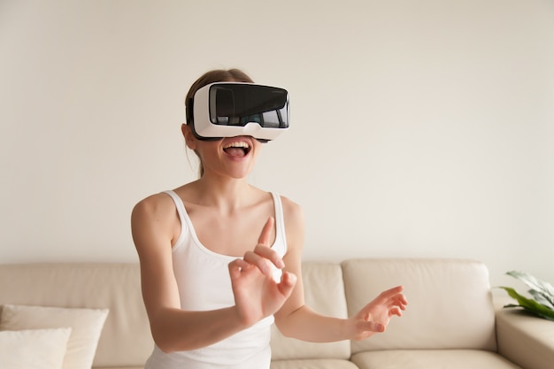 Kostenloses Foto aufgeregte junge frau, die vr-kopfhörer rührende virtuelle realität trägt