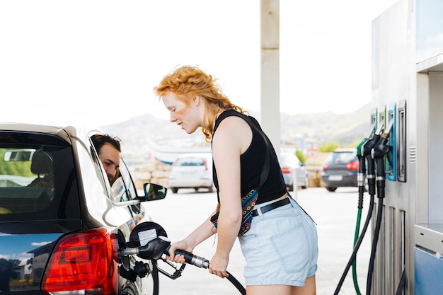 Kostenloses Foto betankendes auto der redheaded frau an der tankstelle