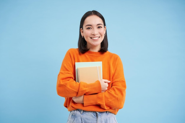 Kostenloses Foto bildung und studenten die glückliche asiatische frau, die notizbücher hält und in die kamera lächelt, genießt goi