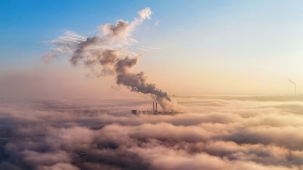 Kostenloses Foto blick auf eine wärmestation in der ferne über den wolken, rauchsäulen, ökologieidee