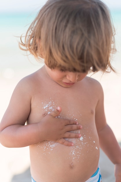 Kostenloses Foto blondes kind am mittleren schuss des strandes