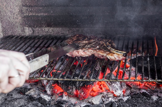 Kostenloses Foto bratenfleisch der menschlichen hand im grillgrill