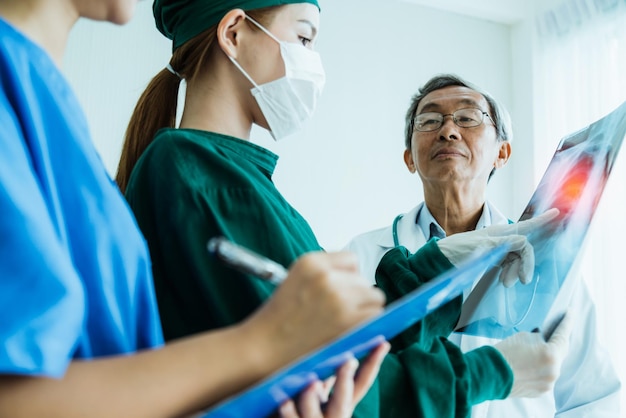 Kostenloses Foto das asiatische ärzteteam untersucht den röntgenfilm der patientenanalyse, um die beste lösung für die operation zu finden und das konzept der gesundheitsideen zu behandeln