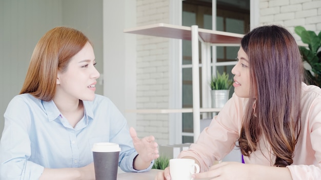 Kostenloses Foto die asiatischen geschäftsfrauen, die warmes kaffee trinkend genießen, besprechen sich über arbeit und geschwätz-klatsch