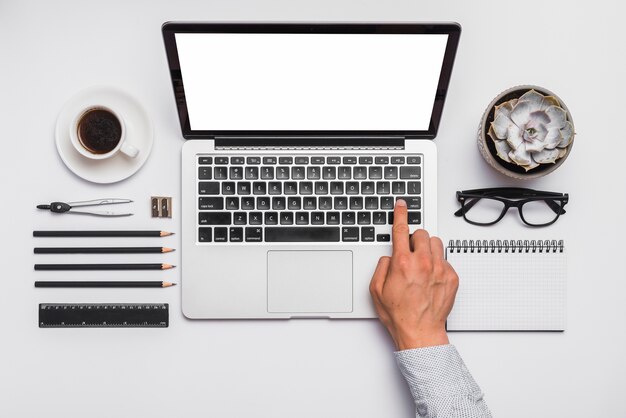 Die Hand des Mannes auf Laptoptastatur über Schreibtisch mit vereinbarten Bürobriefpapier