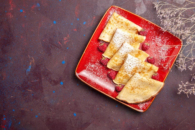 Kostenlose Foto draufsicht auf leckere süße pfannkuchen im roten teller mit himbeeren auf schwarz