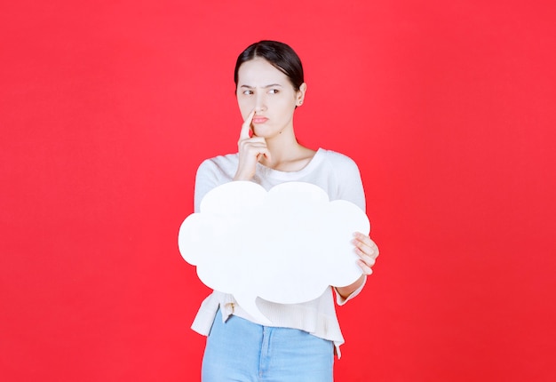 Kostenloses Foto durchdachte junge frau, die ideentafel in einer wolkenform hält