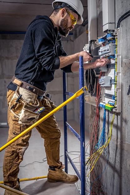 Kostenloses Foto ein elektriker arbeitet in einer schalttafel mit einem elektrischen anschlusskabel.