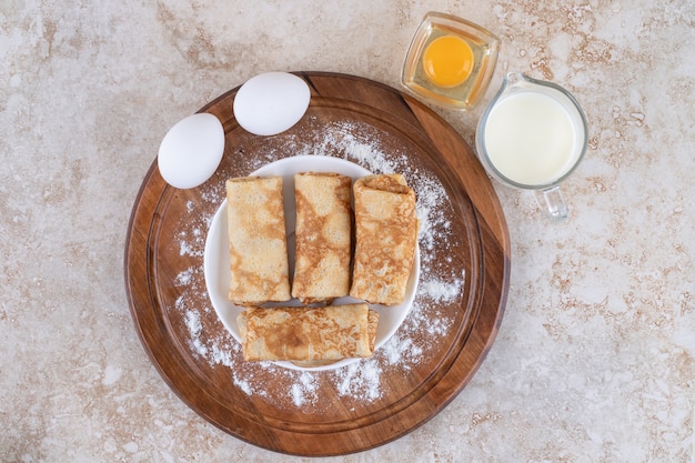 Kostenlose Foto ein holzbrett mit leckeren crepes und rohen eiern