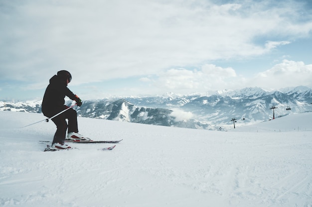 Kostenloses Foto ein junger mann, der auf den im schnee bedeckten bergen ski fährt