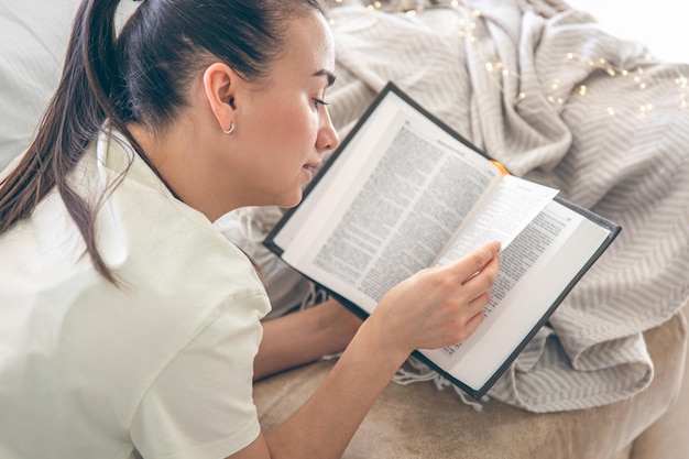 Kostenloses Foto eine frau liest zu hause ein buch und liegt auf dem sofa