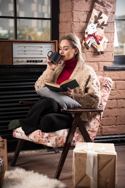 Kostenloses Foto eine frau sitzt und liest buch und trinkt kaffee