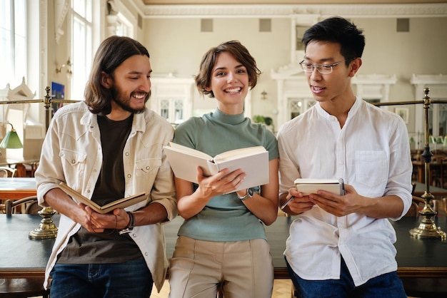 Kostenloses Foto eine gruppe junger multinationaler studenten, die freudig mit büchern lernen und gemeinsam notizen in der bibliothek der universität machen