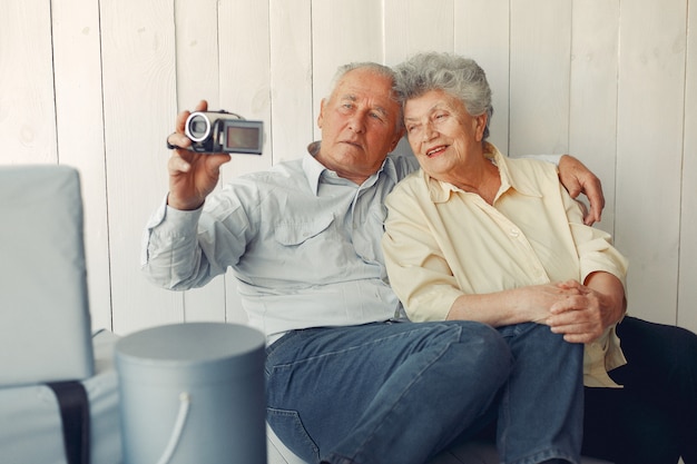 Kostenloses Foto elegante alte paare, die zu hause sitzen und eine kamera verwenden