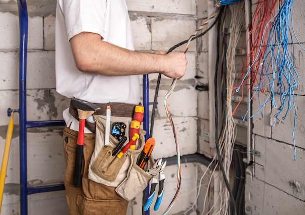 Kostenloses Foto elektriker arbeitet in der nähe der platine mit drähten. installation und anschluss von elektrik.