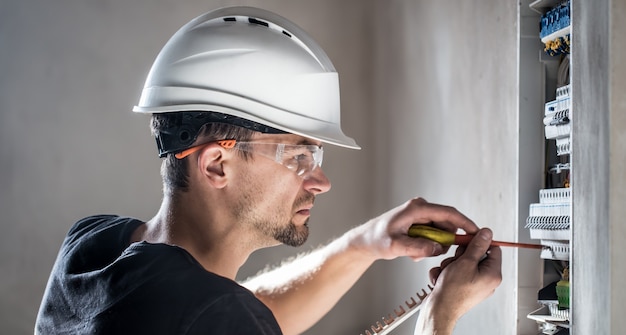 Kostenloses Foto elektrotechniker, der in einer schalttafel mit sicherungen arbeitet. installation und anschluss von elektrischen geräten.