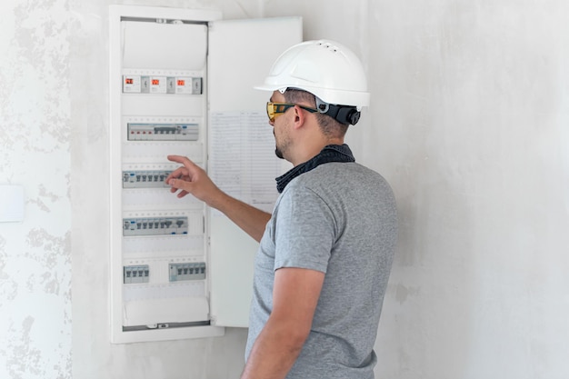 Kostenloses Foto elektrotechniker sieht konzentriert aus, während er in einer schalttafel mit sicherungen arbeitet