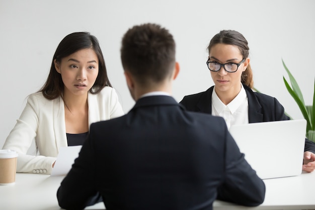 Kostenloses Foto ernste nicht überzeugte verschiedene hr-manager, die einen männlichen bewerber interviewen