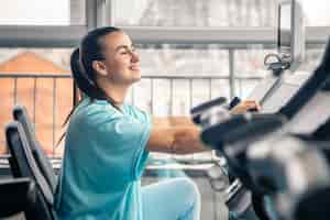 Kostenloses Foto fitnessfrau auf dem fahrrad, die im fitnessstudio cardio-training macht