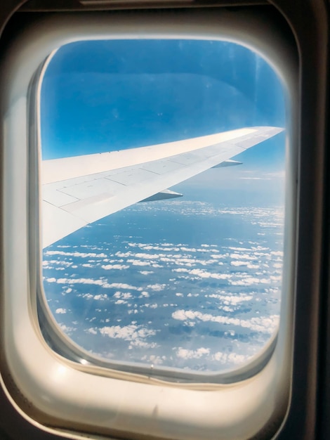 Kostenloses Foto flügel durch das fenster des flugzeugs im atemberaubenden himmel bei sonnenuntergang