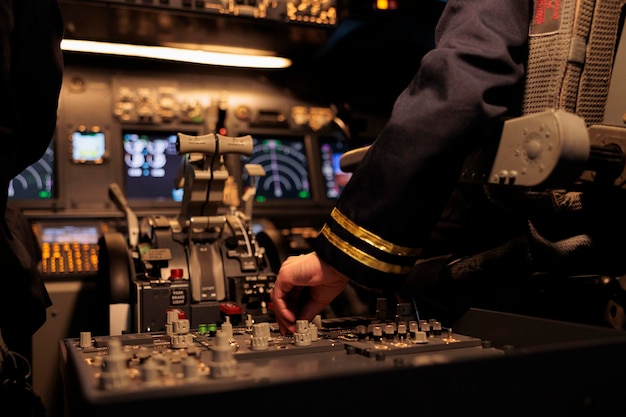 Kostenloses Foto flugzeugbesatzungsmitglied, das den befehl des bedienfelds in der dashboard-navigation verwendet, um ein flugzeug im cockpit zu fliegen. weibliches verkehrsflugzeug in der kabine mit motor und schalthebel. nahansicht.