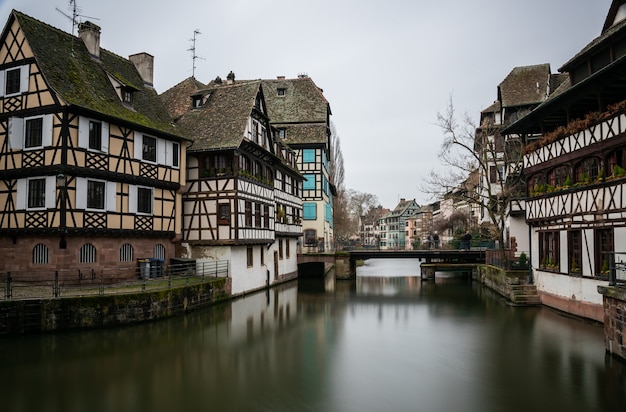 Kostenloses Foto fluss umgeben von gebäuden in petite france unter einem bewölkten himmel in straßburg in frankreich