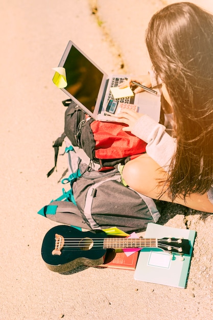 Kostenloses Foto frau, die eigenhändig kenntnisse mit taschenrechner auf laptop am sonnigen tag nimmt