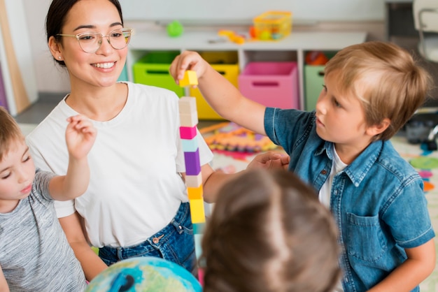 Kostenloses Foto frau, die kinder lehrt, wie man mit buntem turm spielt