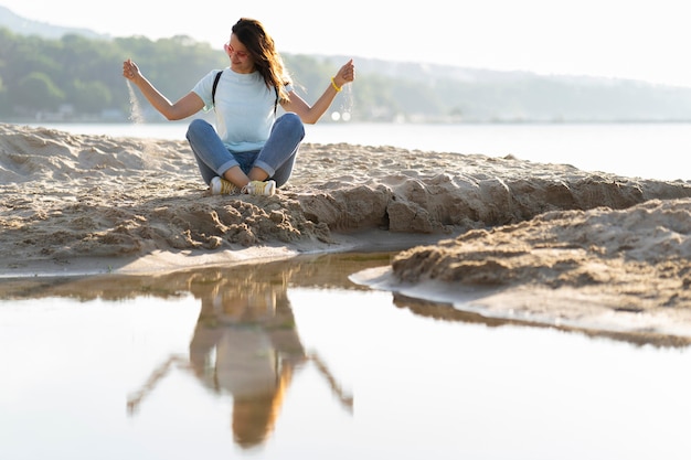 Kostenloses Foto frau, die mit sand am strand spielt