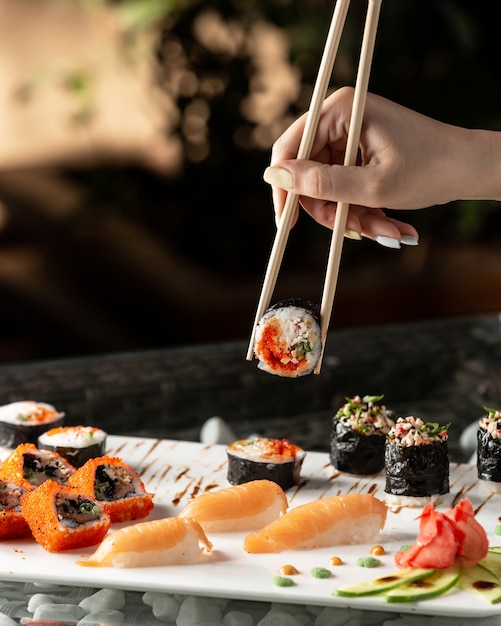 Frau, die Sushi-Rolle mit Stäbchen hält