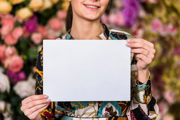 Kostenloses Foto frau, die unbelegtes papier im grünen haus anhält