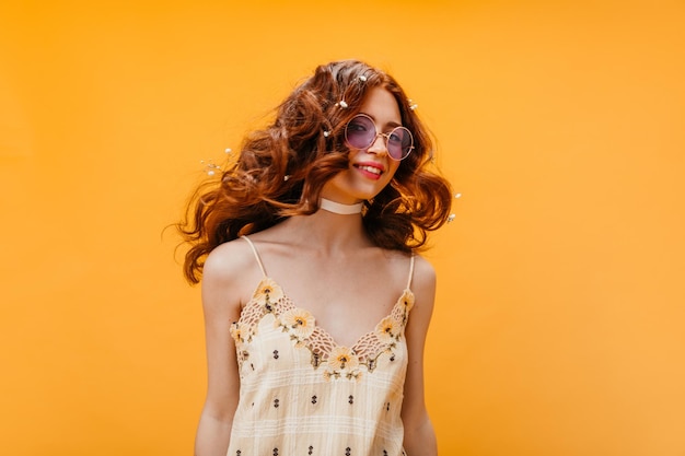 Kostenloses Foto frau mit sonnenbrille und gelbem blumentop spielt haare auf orangefarbenem hintergrund