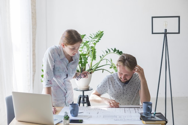 Kostenloses Foto frau und mann, die plan beim arbeiten im büro betrachten