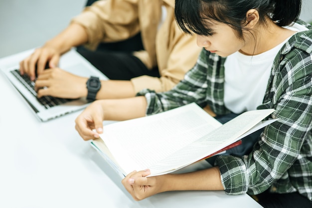 Kostenloses Foto frauen lesen bücher und männer suchen mit laptops in bibliotheken nach büchern.