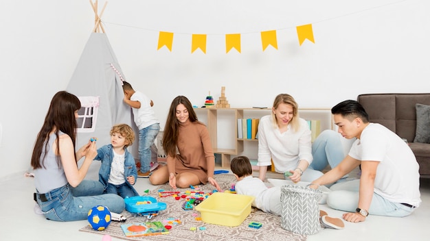 Frauen und Männer spielen mit Kindern zu Hause