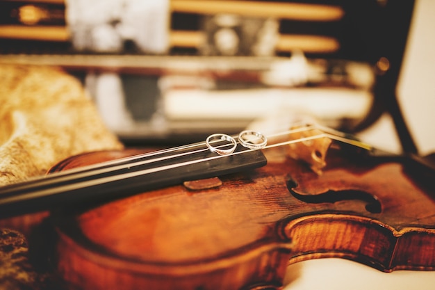 Kostenloses Foto funkelnde eheringe liegen auf den violinsaiten