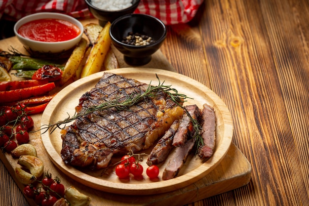 Kostenloses Foto gegrilltes rindersteak auf der dunklen holzoberfläche.