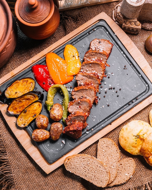 Kostenloses Foto geschnittenes gegrilltes steak auf der holzbrett-auberginenkartoffelbel-pfeffer-draufsicht