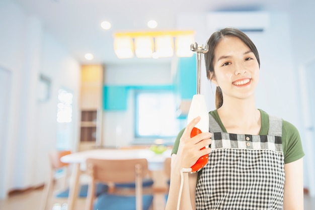 Kostenlose Foto glückliche dame, die küchenmaterial über kopienraumhintergrund hält